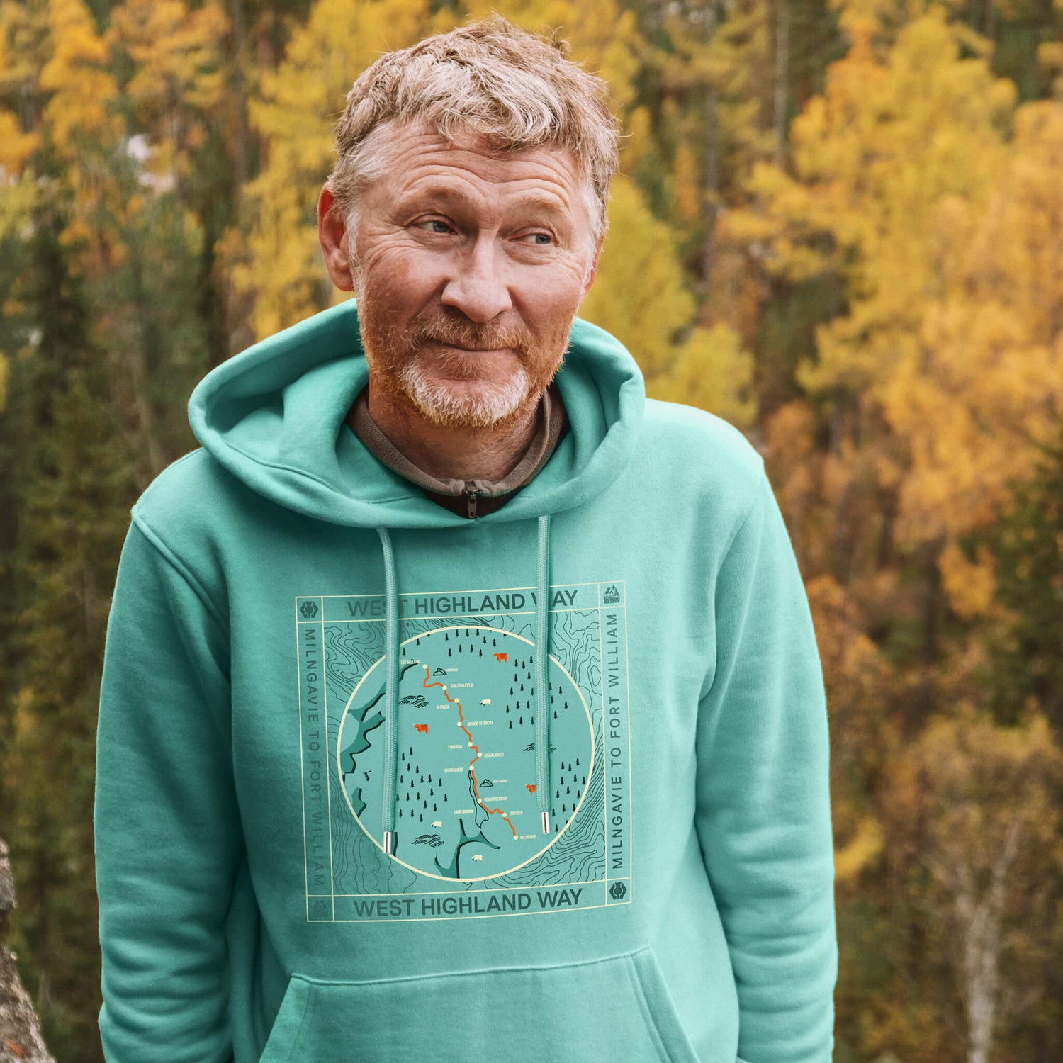 Man wearing a teal hoodie with West Highland Way map design on the front